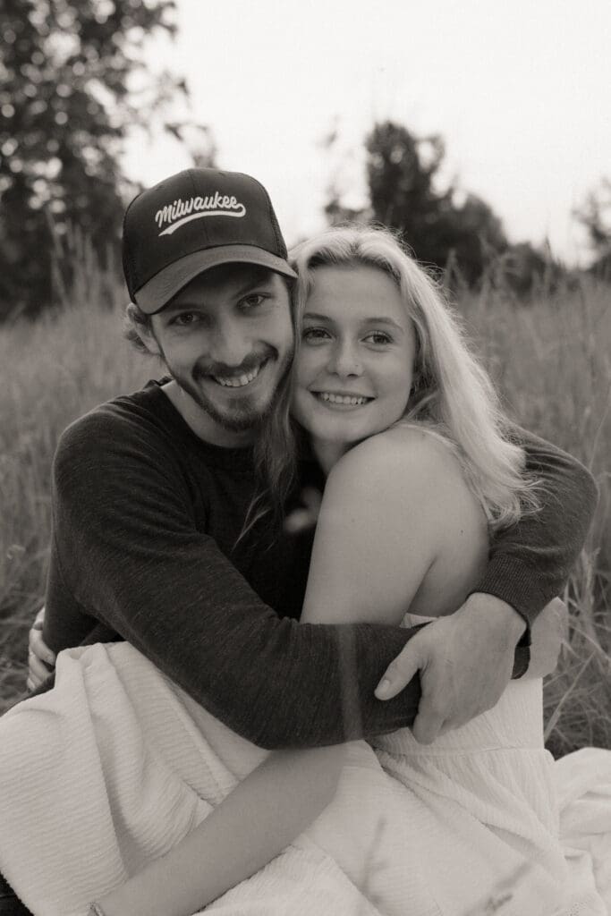 A black and white image of a couple sitting in a field.