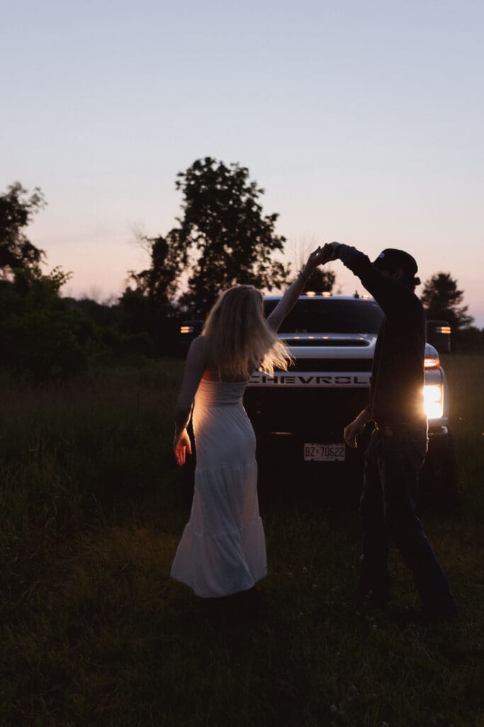 A couple dancing in a field during blue hour.